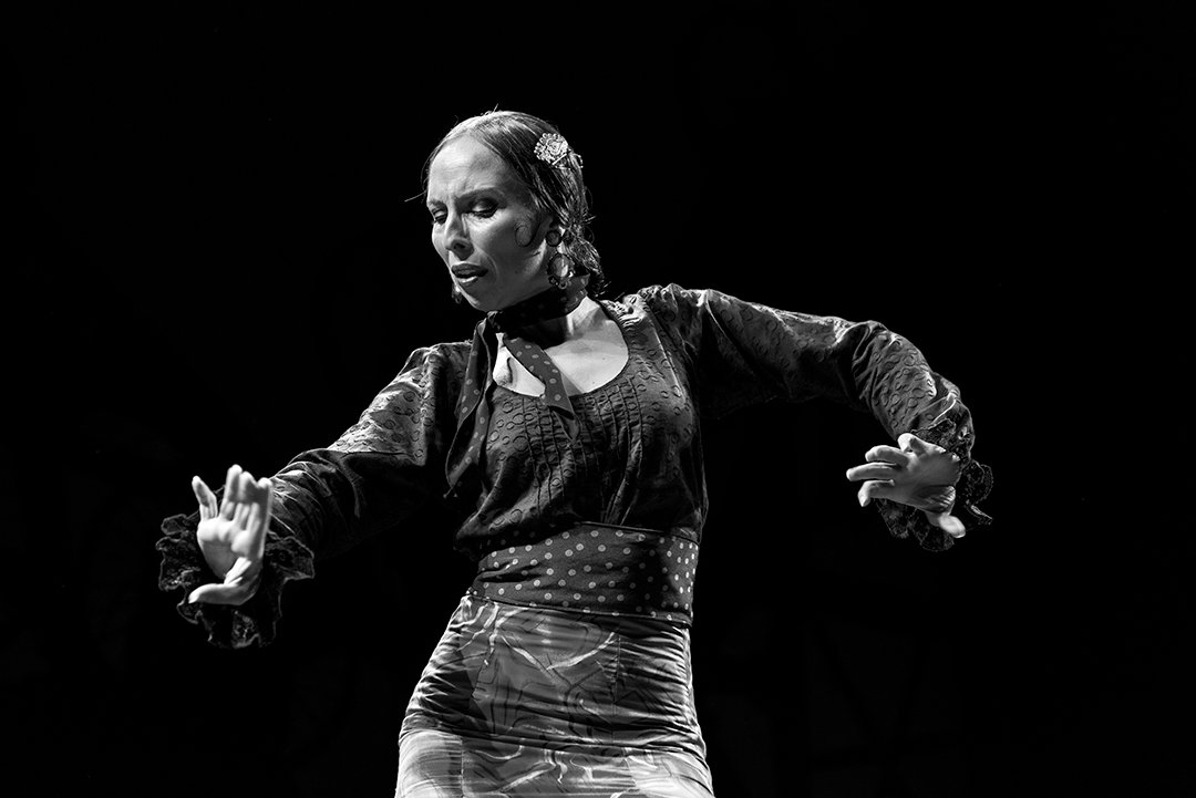 Una bailarina con los brazos extendidos en el escenario.
